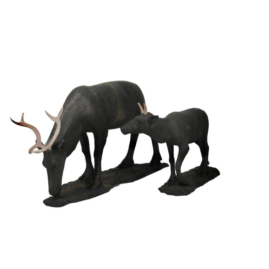 One original hand-carved sculpture by Inuit artist, Paul Malliki. Two caribous carved out of basalt.