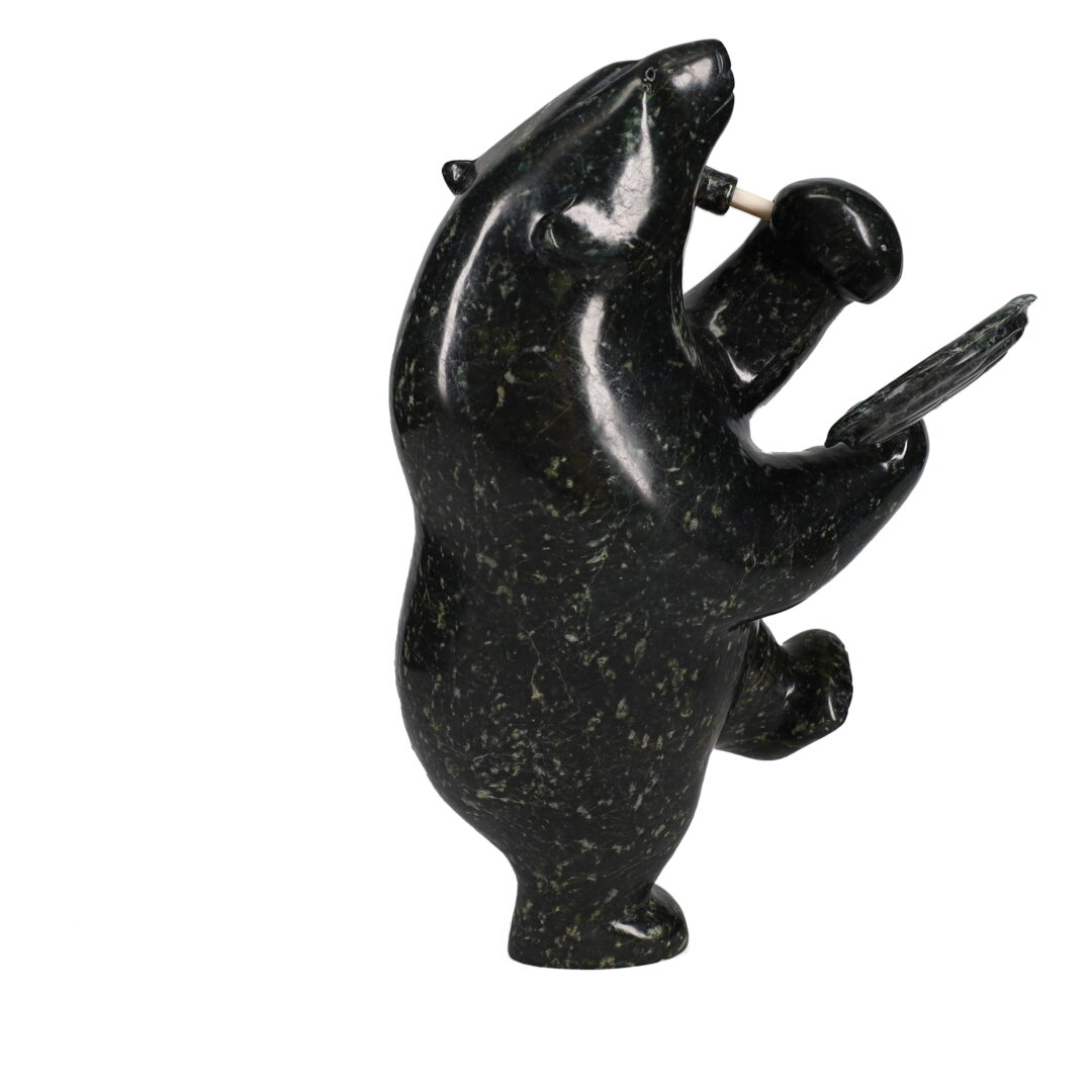 One original hand-carved sculpture by Inuit artist Etidloie Adla. One drum dancing polar bear carved out of serpentine.