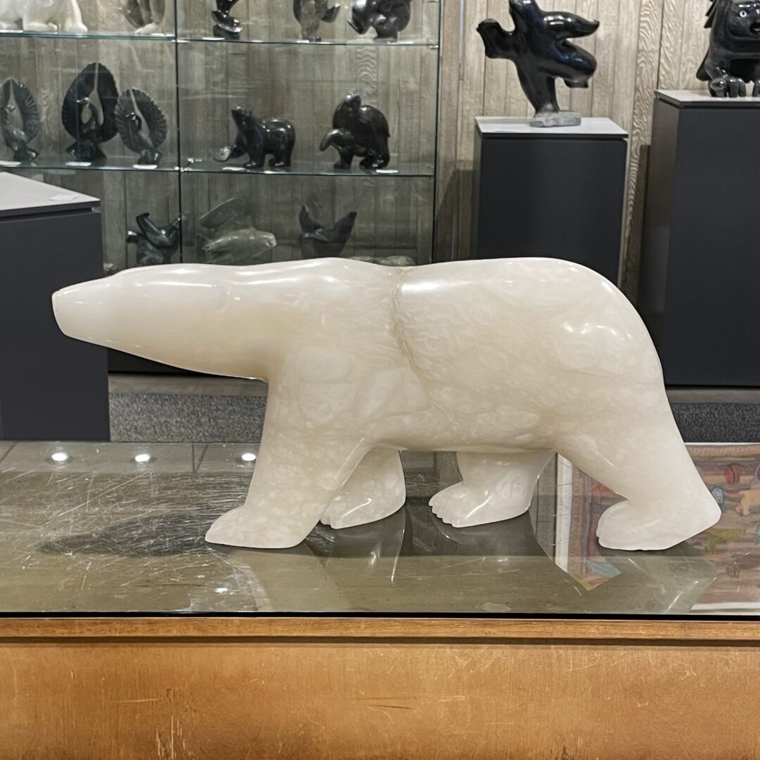 One original hand-carved sculpture by Inuit artist, Koomuatuk Sapa Curley. One walking bear carved out of alabaster.
