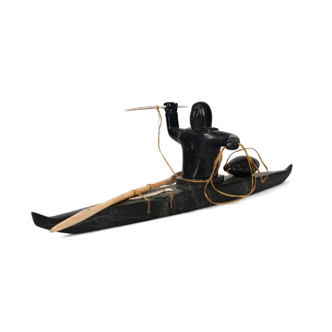 One original hand-carved sculpture by Inuit artist, Noah Jaw. One kayaker carved out of serpentine and wood.
